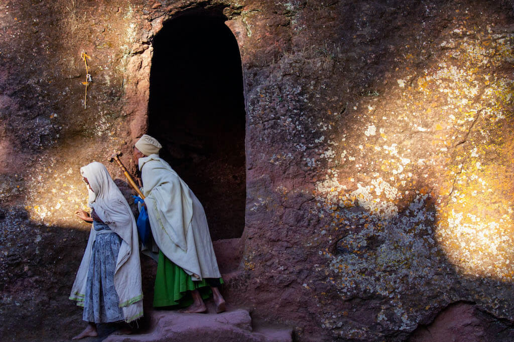 Gläubige Pilger küsst die Felswand beim Morgengebet in Felsenkirche in Lalibela - Äthiopien Reisebericht in Bildern