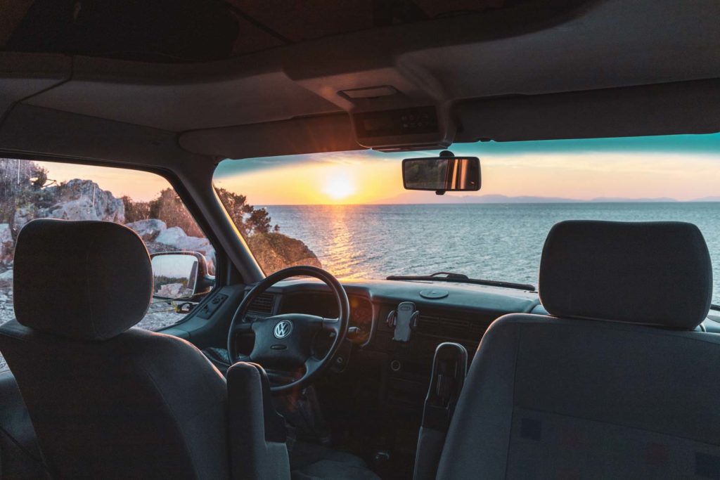 Wildcampen am Meer in Griechenland mit VW Bus und Blick auf Sonnenuntergang aus dem Bus heraus