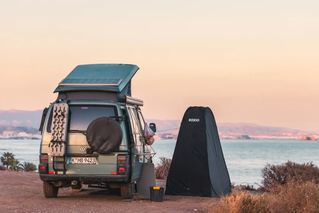 Pop-up Duschzelt/Toilettenzelt Boxio Tent mit VW Bus am Meer bei Sonnenenuntergang