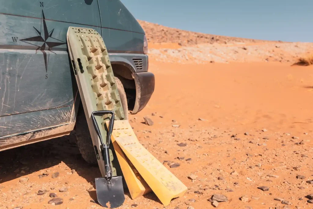 Sandbleche aus Kunststoff, Auffahrkeile und Spaten nach Einsatz vor VW Bus in der Wüste Marokkos