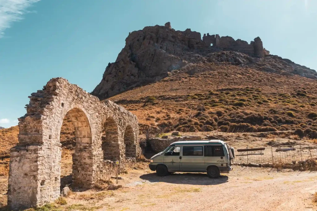 VW Bus vor dem Hügel auf dem das Castello Rosso thront