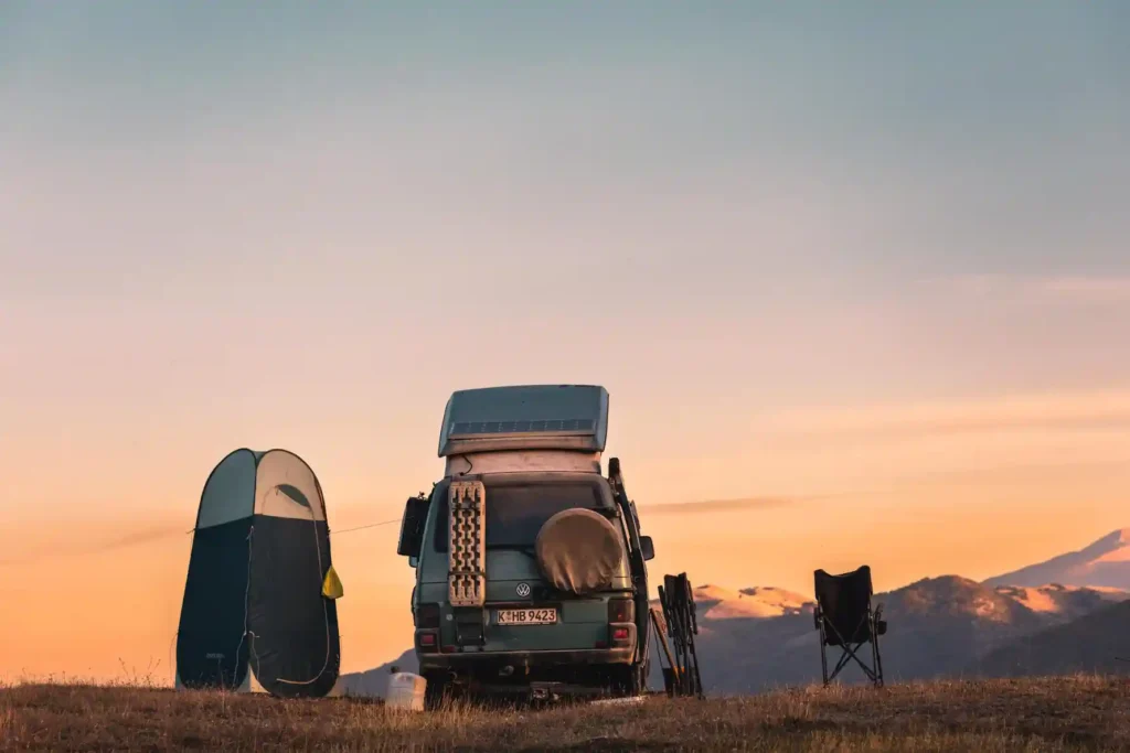 VW Bus Camper mit Po up Duschzelt bei Sonnenuntergang